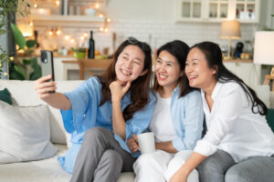 Cheerful middle aged friends enjoying home Birthday holiday party. Asian Friends cheering drinking red wine celebrating Christmas or New Year party.